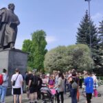 Uczestnicy stoją przed pomnikem Adama Mickiewicza