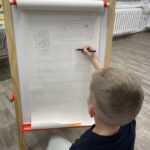 Chłopiec rysuje na tablicy swój projekt planszy do gier.