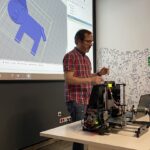 Prowadzący prezentuje drukarkę do drukowania obiektów 3D