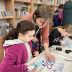 Bibliotekarka instruuje dziewczynce wykonania oprawy okularowe techniką 3D