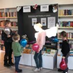 Dzieci trzymają baloniki i przeglądają książki