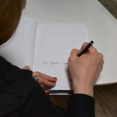 Autorka podpisuje książkę - widok na otwartą książkę z podpisanymi tekstami