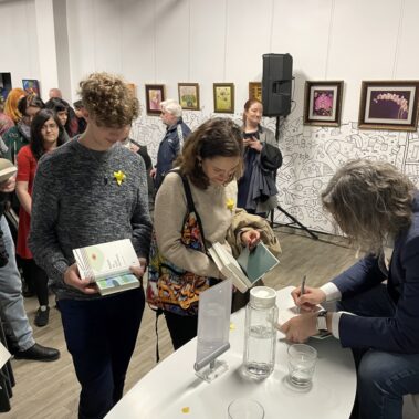 Autor podpisuje książkę, i kolejka czytelników