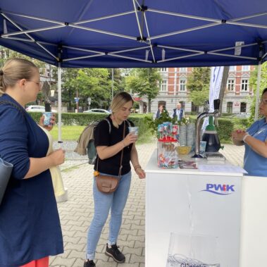 Dorośli piją napój ze stoiska PWiK