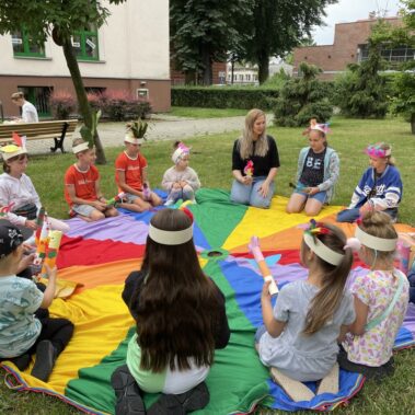 Dzieci siedzą wokół płachty.