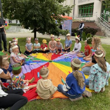 Dzieci siedzą wokół płachty.