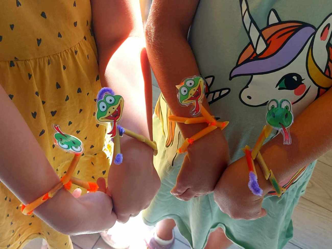 Dziewczynki prezentują bransoletki z wężami na rękach.