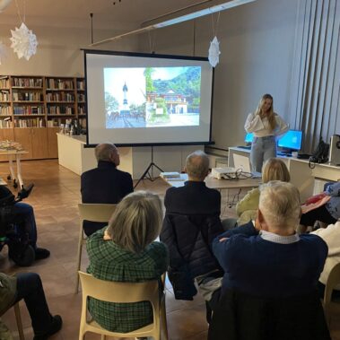 Widok ogólny na spotkanie obok ekranu stoi prelegentka.