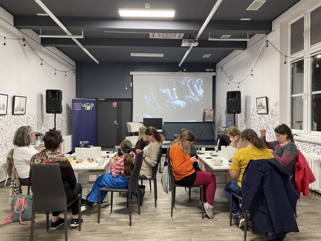 Uczestniczki haftują i oglądają film z życia wsi Schönwaldu