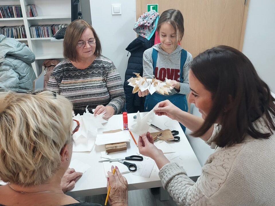 Uczestniczki przy pracy, dziewczynka już rozkłada papiery w gwiazdkę