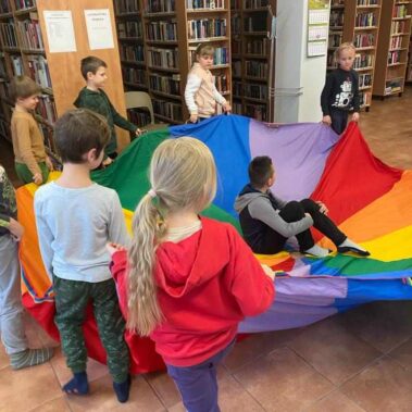 Dzieci obracają płachtę, na której siedzi chłopiec