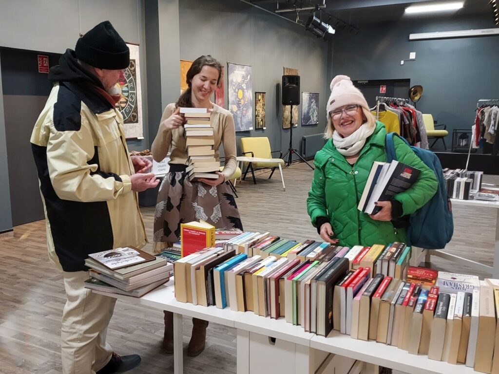 Goście w towarzystwie bibliotekarki wybierają książki
