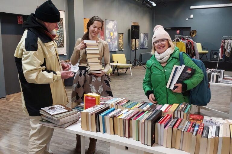 Goście w towarzystwie bibliotekarki wybierają książki