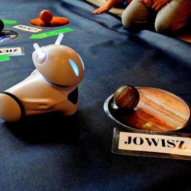 Robot Photon stoi obok planszy i kulki - modelu Jowisza