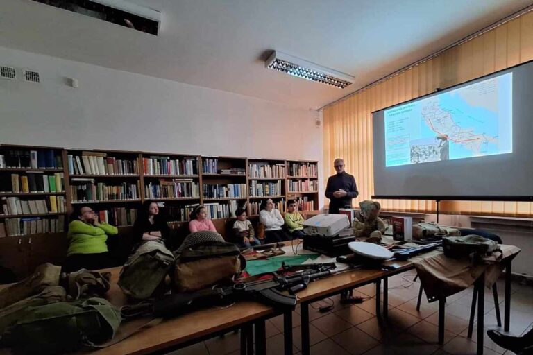 Prowadzący omawia historię, na ekranie mapa Włoch z zaznaczoną trasą, na stole leżą różne rzeczy