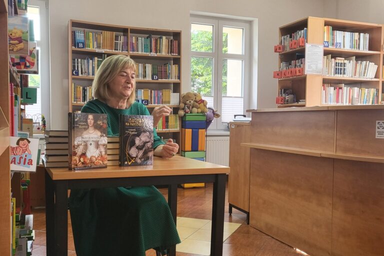 Garbiela Anna Kańczor. Siedzi przy stoliku z swoimi książkami.