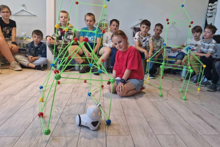 Robot Photon porusza się wśród stacji kosmicznej. Dzieci oglądają