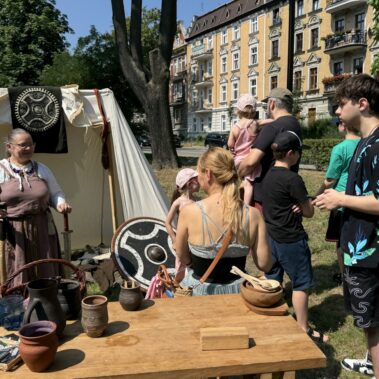 Stoisko Wikingów z Drużyny Utgard, na stole leżą garnki z gliny, w tle namiot z panią, którą trzyma bronie Winkingów