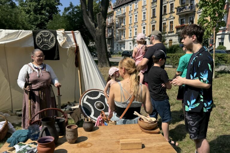 Stoisko Wikingów z Drużyny Utgard, na stole leżą garnki z gliny, w tle namiot z panią, którą trzyma bronie Winkingów