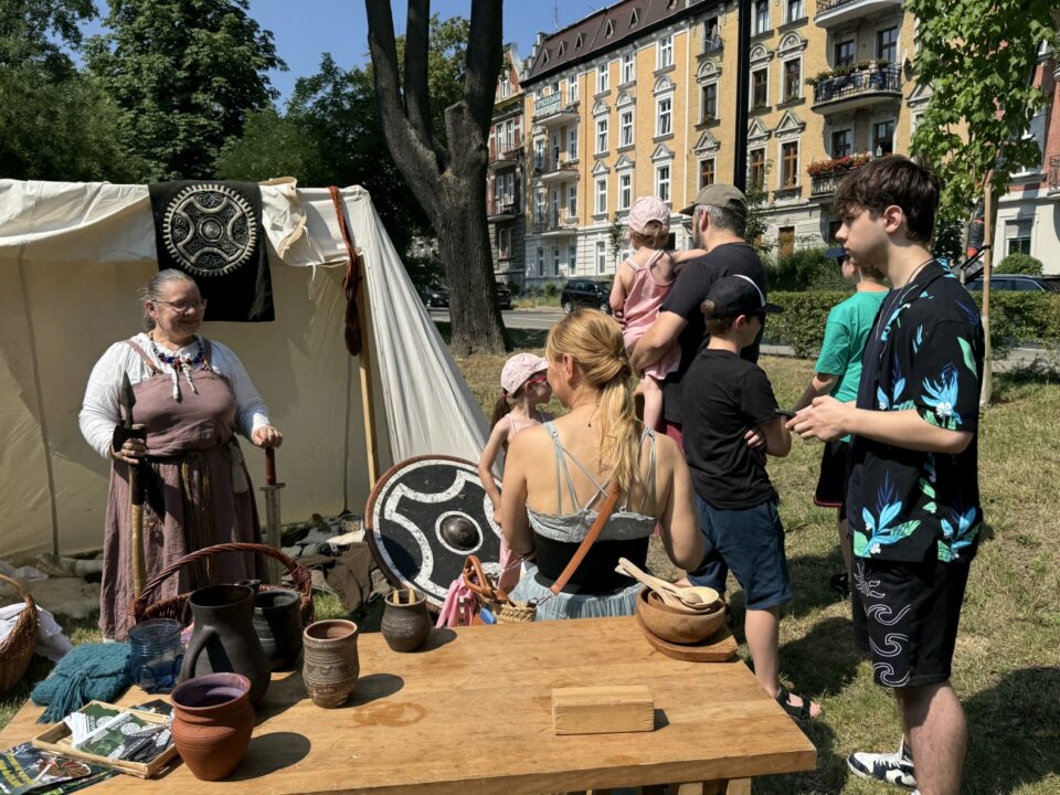 Stoisko Wikingów z Drużyny Utgard, na stole leżą garnki z gliny, w tle namiot z panią, którą trzyma bronie Winkingów