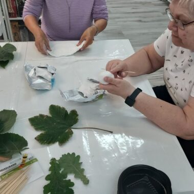 Panie przygotowują masę, na stole leżą naturalne liście