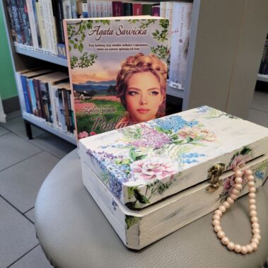 Skrzynka z decoupage i wystającymi koralikami i książką w tle
