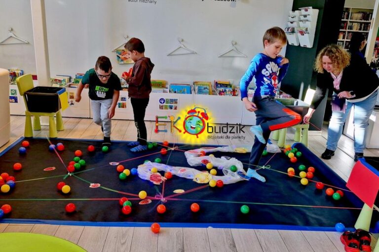 Chłopcy wykonują zadania nad imitacją oceanu z planszy i piłeczek, rysunków ryb