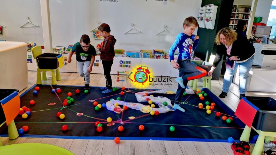 Chłopcy wykonują zadania nad imitacją oceanu z planszy i piłeczek, rysunków ryb