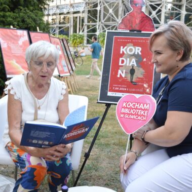 Pani czyta książkę w towarzystwie bibliotekarki.
