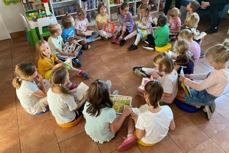 Dzieci siedzą w kółko i czytają książki