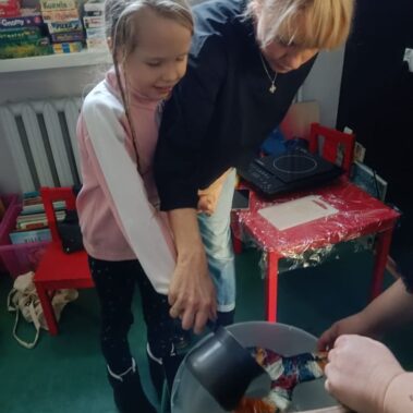 Opiekunka pomaga dziewczynce w wlaniu wosku