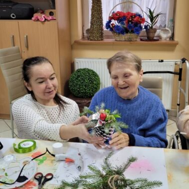 Seniorka z bibliotekarką robią ozdobę z szyszki