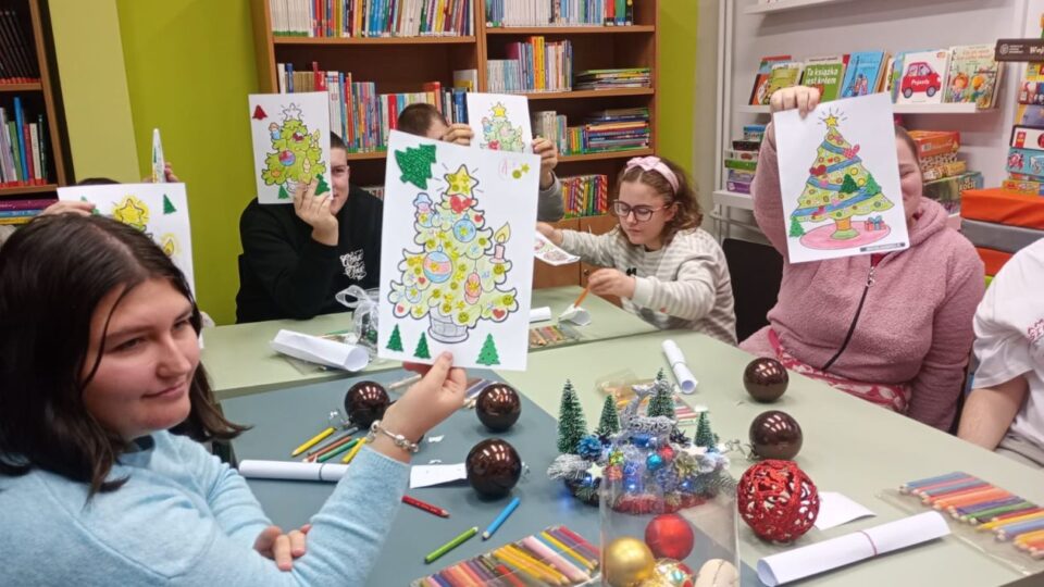 Dzieci pokazują swoje kolorowanki z motywem choinki