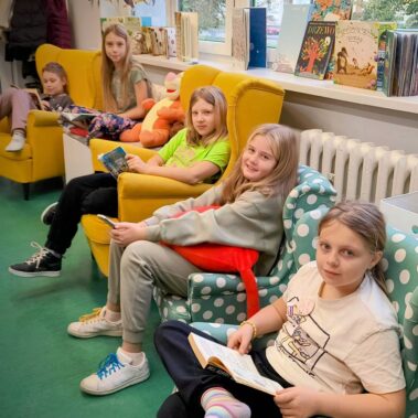 Dzieci siedzą na fotelach i czytają książki