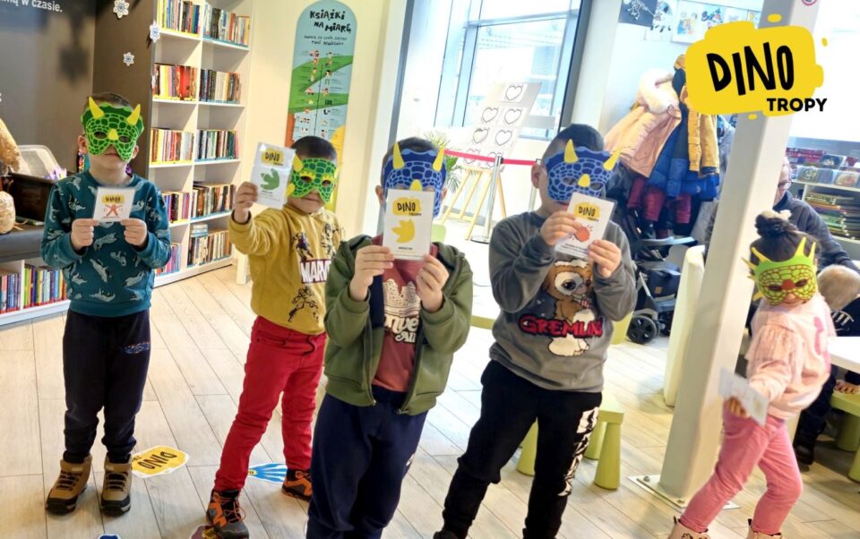 Dzieci w maskach dinozaurów prezentuje swoje kartki z wzorami tropów