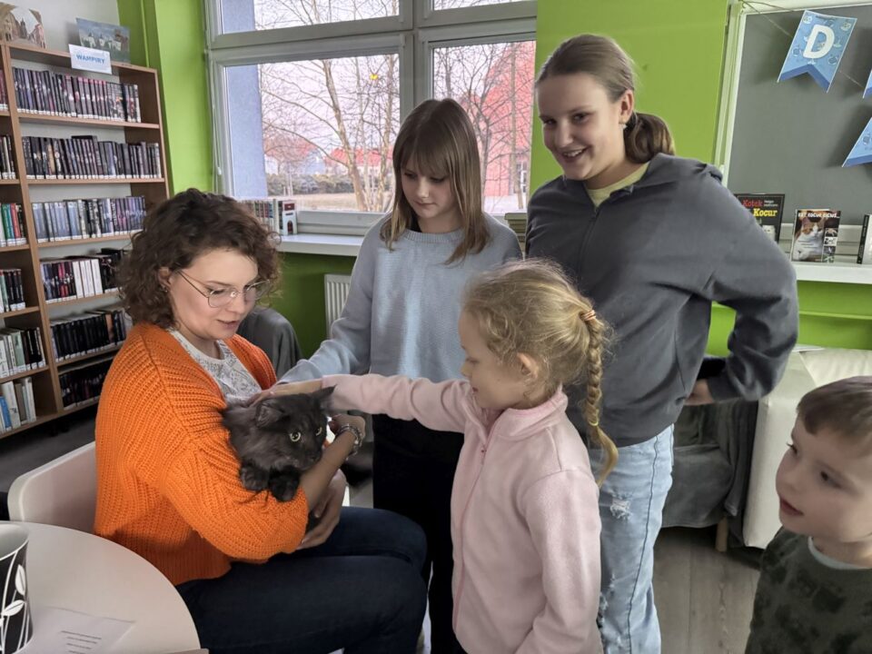 Katarzyna Łomazka i jej kot, dziewczynka go głaszcze, dzieci przyglądają