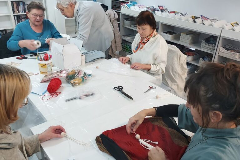 Seniorki przy pracy, na stole leżą różne materiały