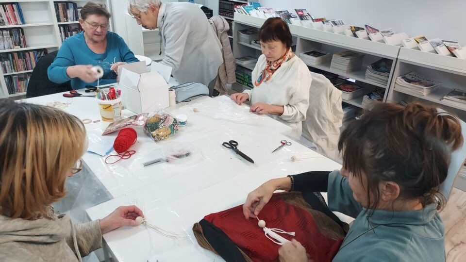 Seniorki przy pracy, na stole leżą różne materiały