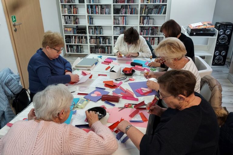 Seniorki przy pracy, na stole leżą materiały
