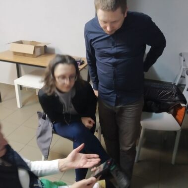 Starsza pani pokazuje uczestnikom zdjęcia na smartfonie