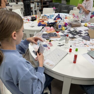 Dziewczynka wycina z papieru, na stole leżą różne materiały