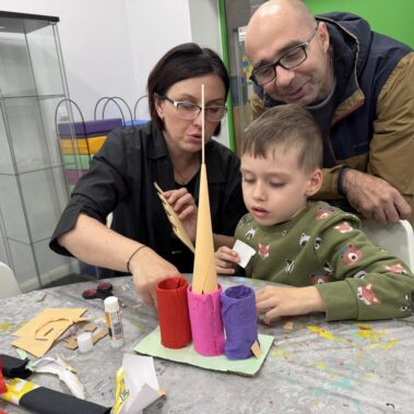 Rodzice z chłopcem budują organizera na przybory szkolne w kształcie zamku
