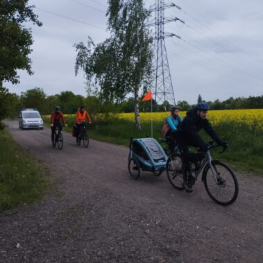 Uczestnicy jeżdżą rowerami po drogach polnych i towarzyszą im Straż Miejska
