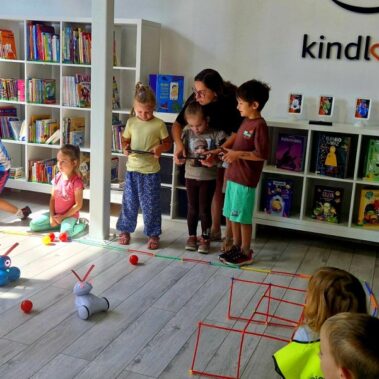 Dwie drużyny rywalizują sterując robotami. Po podłodze roboty poruszają pchając kulki.