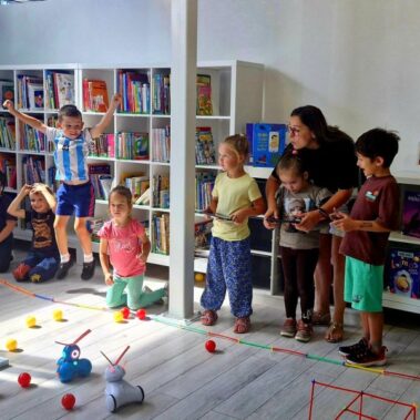 Dwie drużyny rywalizują sterując robotami. Po podłodze roboty poruszają pchając kulki.