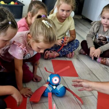 Dzieci ulepszają roboty z użyciem kartek papieru i taśmy klejącej. Aby robot sprawnie chwytał piłkę.