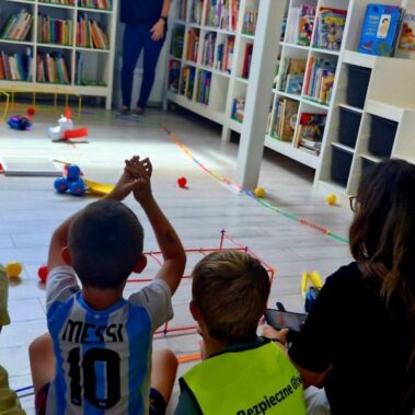 Dwie drużyny rywalizują sterując robotami. Po podłodze roboty poruszają pchając kulki. Chyba już był gol?