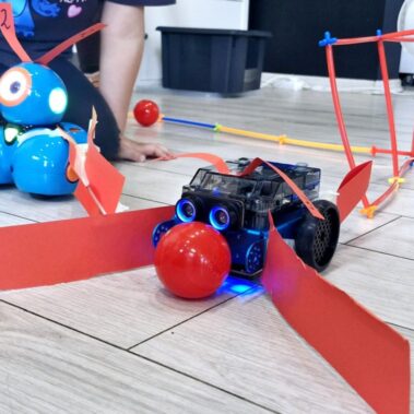 Robot mBot2 z chwytakiem pycha czerwoną kulkę.
