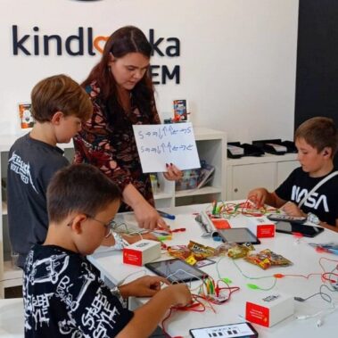 Chłopcy przy pracy nad Makey Makey, prowadząca instruuje.