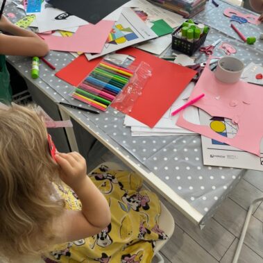 Na stole leżą materiały i dziewczynki przy pracy